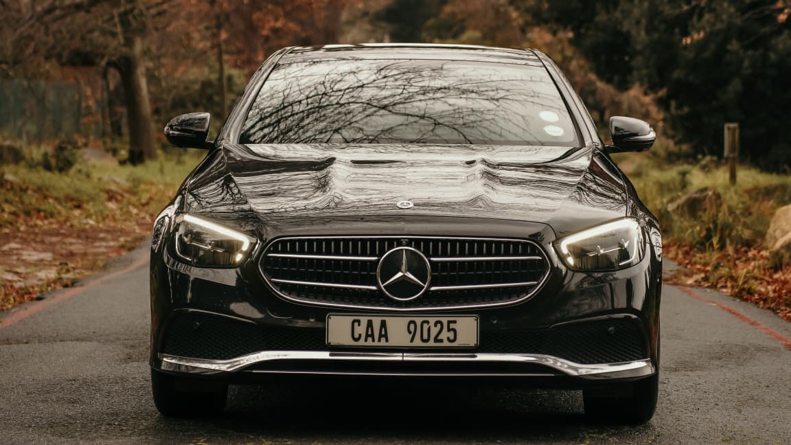 Black Mercedes-Benz E-Class front arrival on a tree-lined Cape Town road