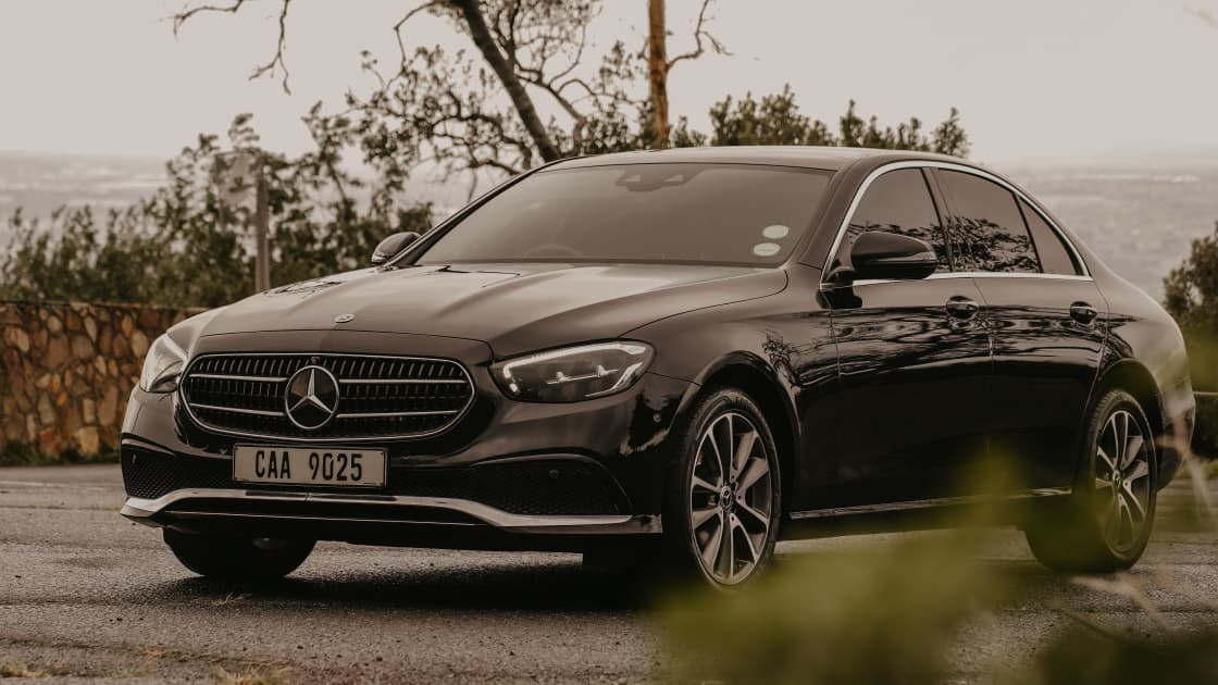 Black Mercedes-Benz E-Class three-quarter profile with Cape Town view