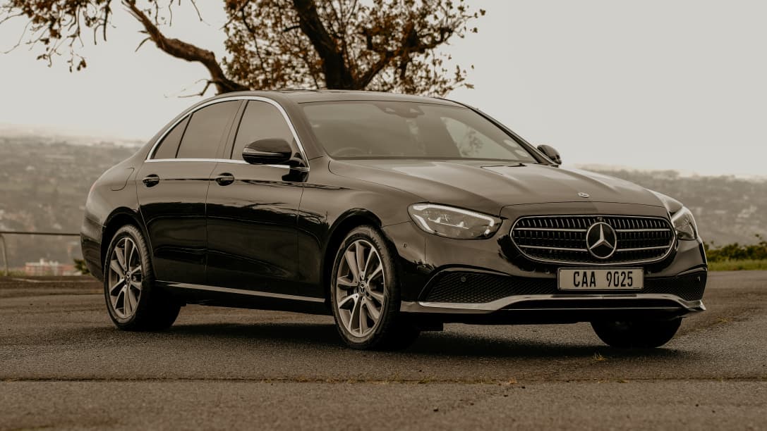 Black Mercedes-Benz E-Class side profile with city view
